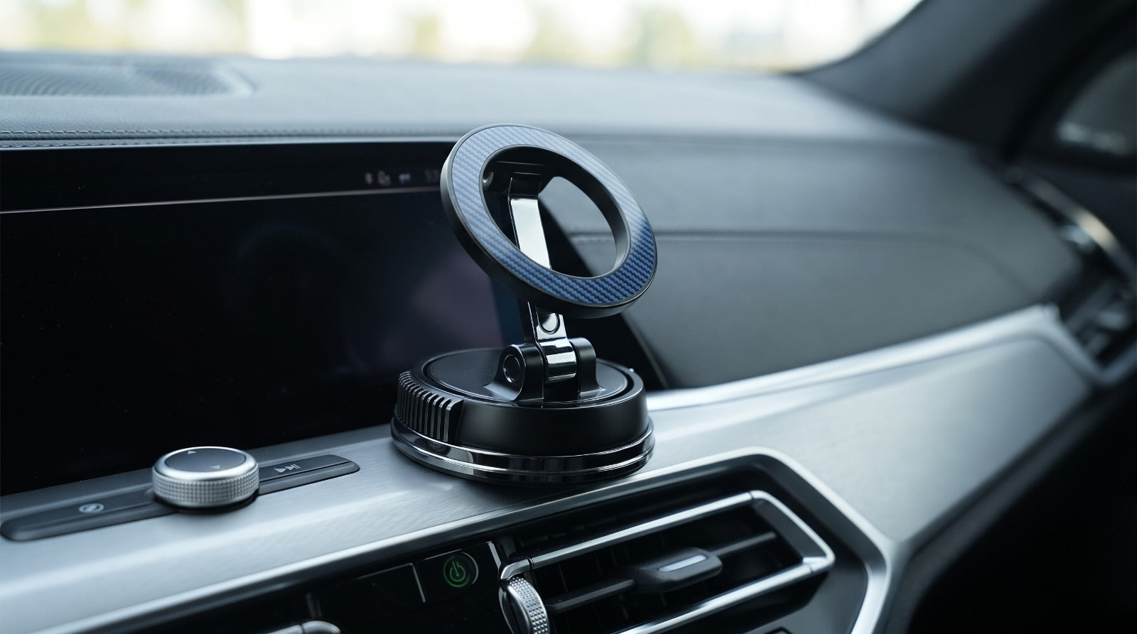 Magnetic MagSafe car phone mount with carbon fiber finish installed on a luxury dashboard.
