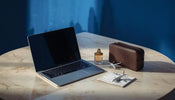 Laptop, perfume and travel bag flat lay representing UAE to India duty-free shopping for electronics and gifts