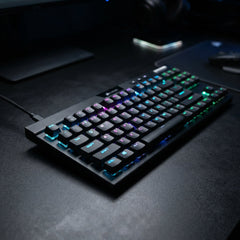 Sleek black mechanical gaming keyboard with vibrant customizable RGB backlighting displayed on a dark textured desk setup.