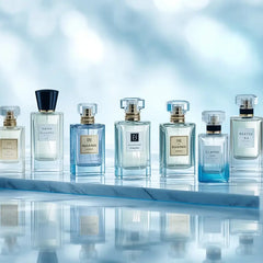 Luxury perfume collection displayed on marble platform with elegant glass bottles and blue reflective background.